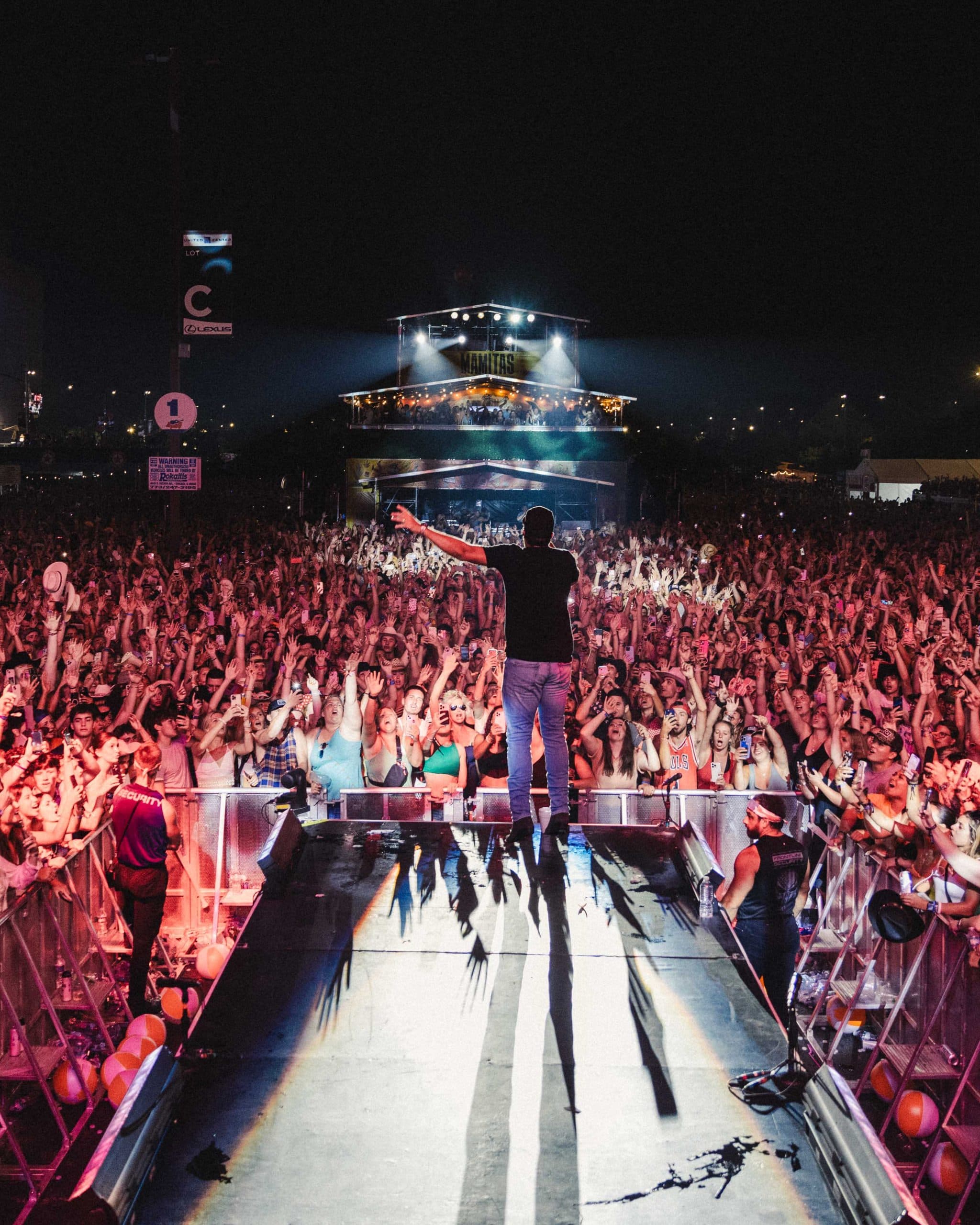 group of people in front of a merch stand bringing their drinks together in a cheers.