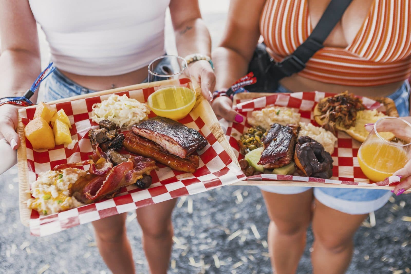 two women holding platers of BBQ food